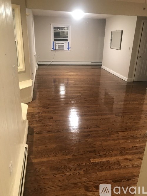 A room with wooden flooring and a window with blue tape on it.