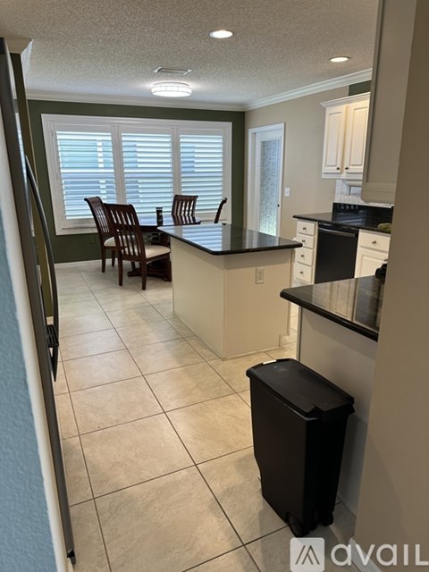 A kitchen with a black counter top and white cabinets.