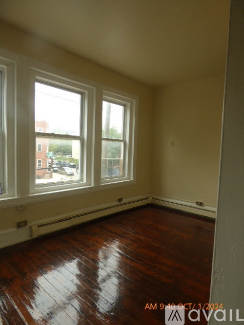 A room with wooden floors and three windows.