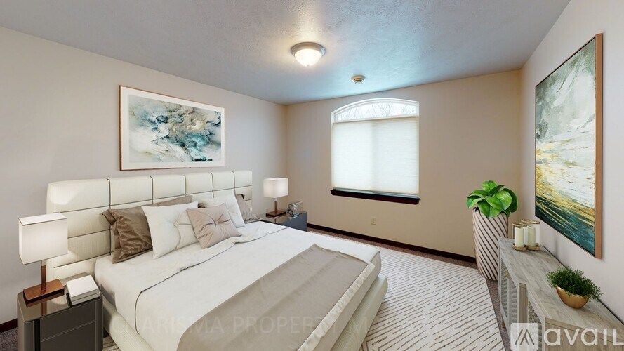 A well-lit bedroom with a large bed and a painting on the wall.