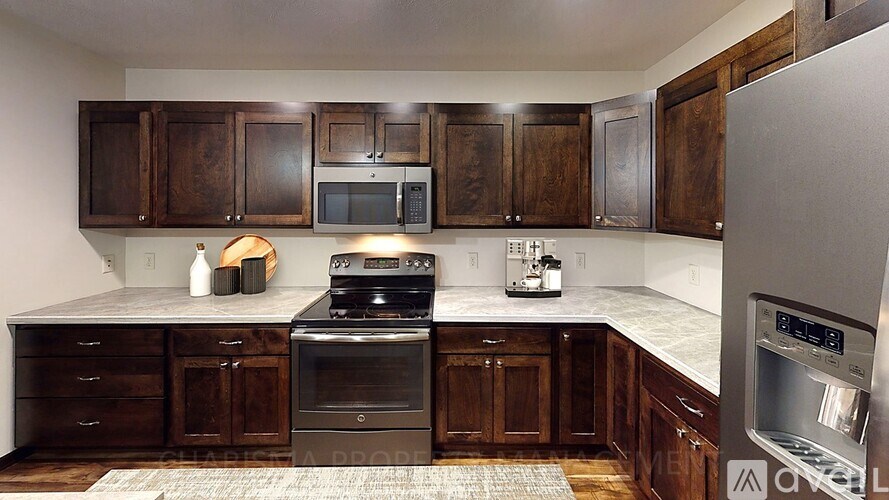 A kitchen with dark wood cabinets and stainless steel appliances.