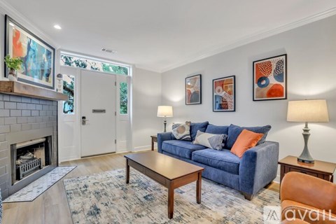 A living room with a blue couch, a fireplace, and a rug.
