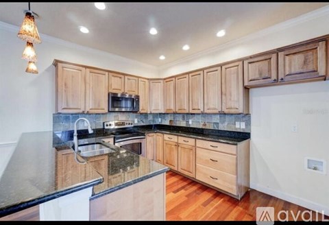 A kitchen with wooden cabinets and a black countertop.