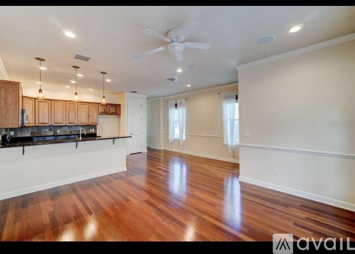 A spacious room with wooden floors and a ceiling fan.