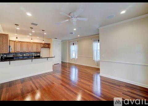 A spacious room with wooden floors and a ceiling fan.