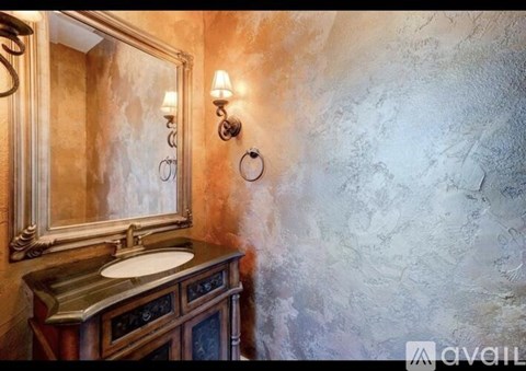 A bathroom with a marble wall and a wooden vanity.