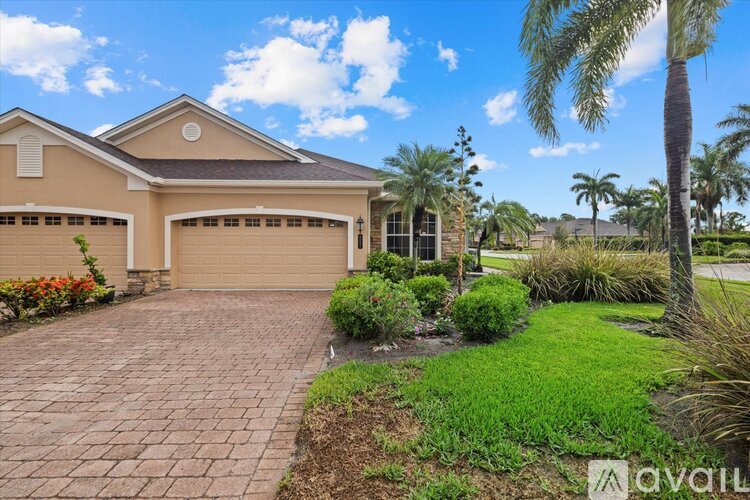 A house with a driveway and palm trees in front.