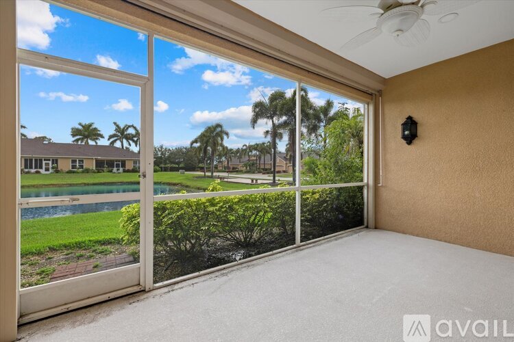 A room with a sliding glass door leading to a pool and palm trees.