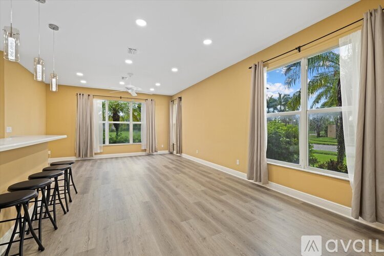 A spacious room with a bar area and a view of the outdoors through the windows.