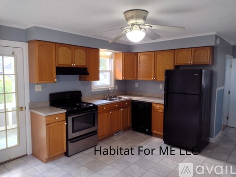A kitchen with wooden cabinets and black appliances is available for rent.