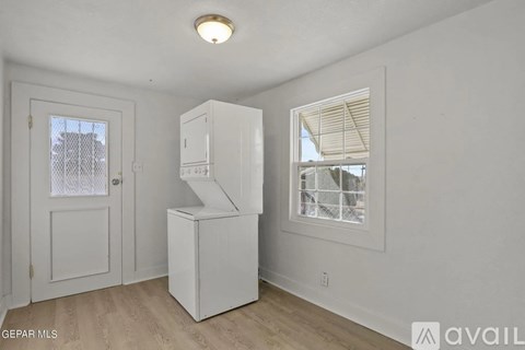 A white kitchen with a refrigerator, sink, and a window with blinds.