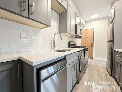 A modern kitchen with a white countertop and stainless steel appliances.