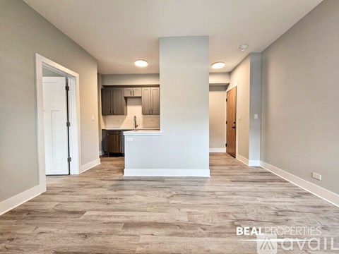 A spacious, empty room with a kitchen area in the background.