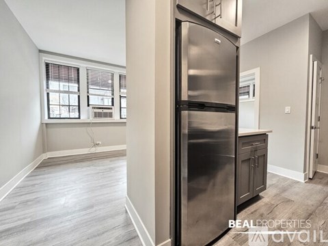 A kitchen with a stainless steel refrigerator and wooden flooring.