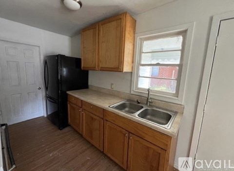 A kitchen with wooden cabinets and a black fridge.