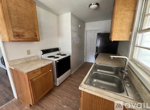 A kitchen with a stove, sink, and cabinets.