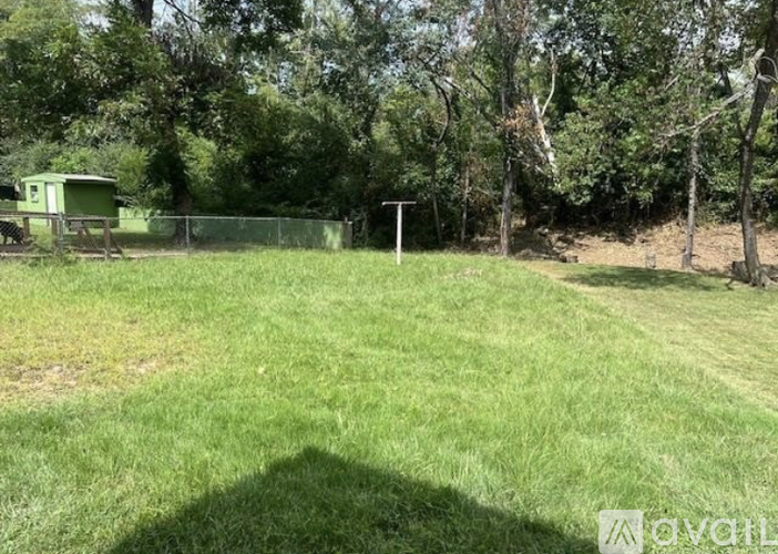 A green field with a fence and a tree in the background.