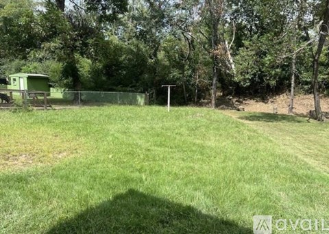 A green field with a fence and a tree in the background.