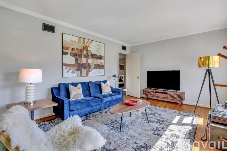 A living room with a blue couch, a wooden coffee table, and a large painting on the wall.