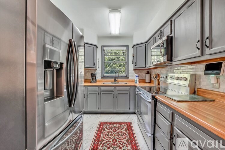 A kitchen with a stainless steel refrigerator and wooden countertops.