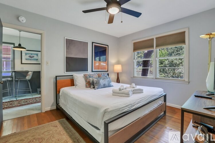A bedroom with a bed, a ceiling fan, and a window.