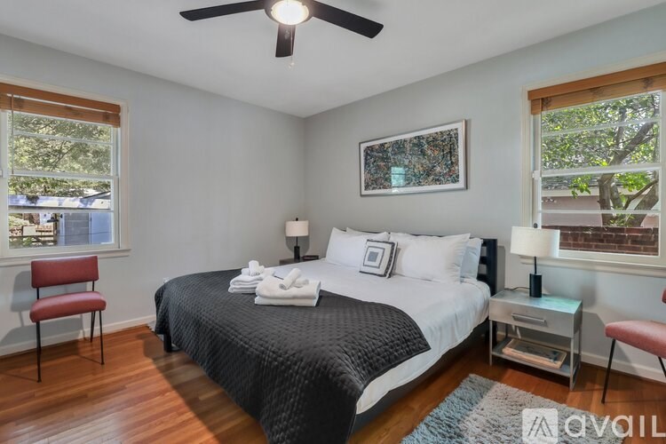 A bedroom with a bed, chair, and window.