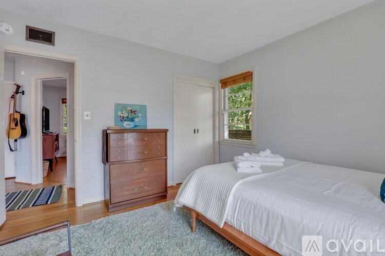 A bedroom with a large bed and a wooden dresser.