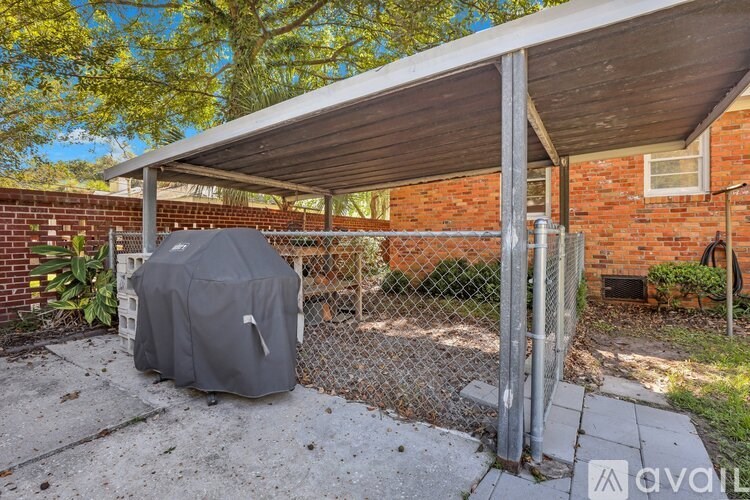 A grey covered grill is in front of a chain link fence.