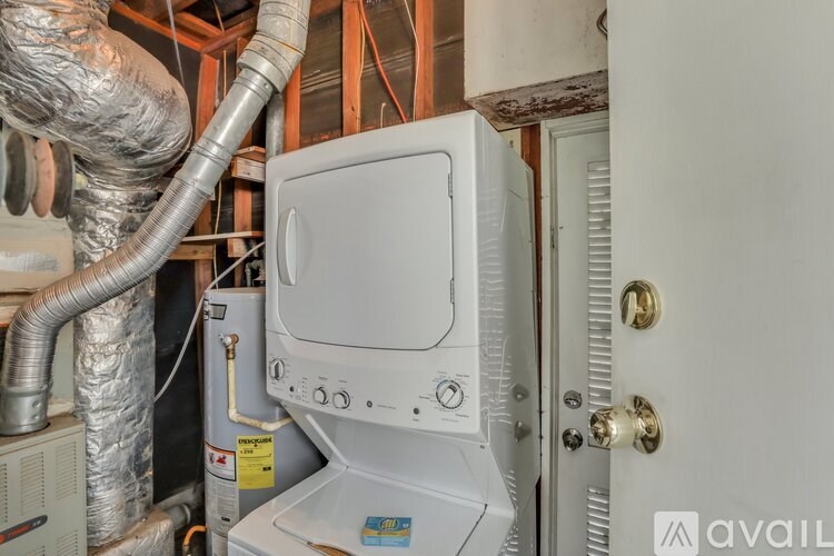 A white box with a door is in a room with pipes.