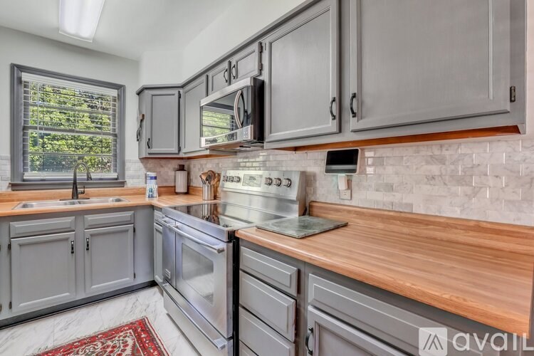 A kitchen with grey cabinets and a wooden countertop.