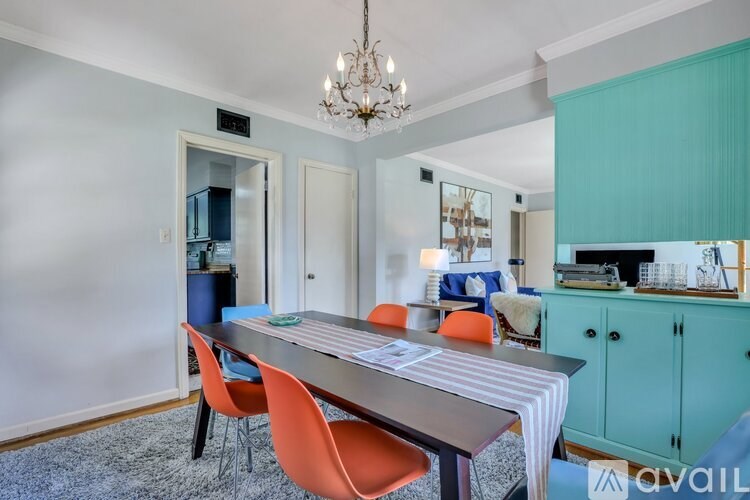 A dining room with a long table and orange chairs.