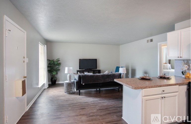 A living room with a black couch and a television on the wall.