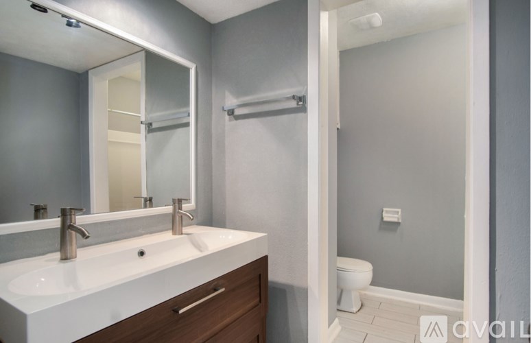 A bathroom with a white sink and a toilet in the background.