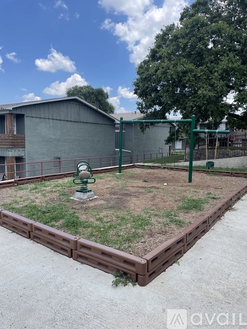 A playground with a green swing set and a small fence.