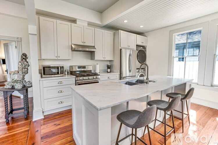 A kitchen with a white island and grey barstools.