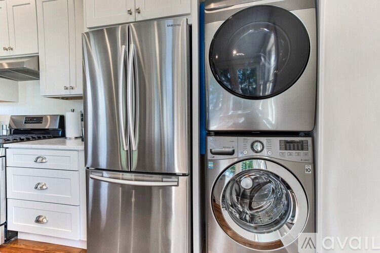 A stainless steel refrigerator and washing machine in a kitchen.