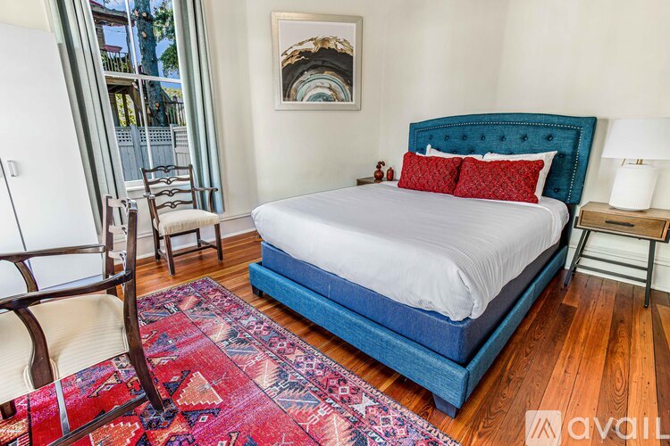 A bedroom with a blue headboard bed and a red rug.