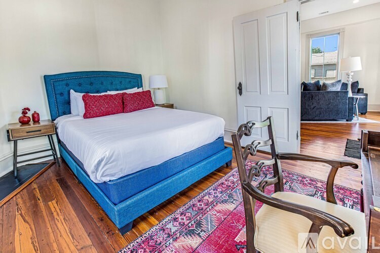 A bedroom with a blue bed and a wooden chair.