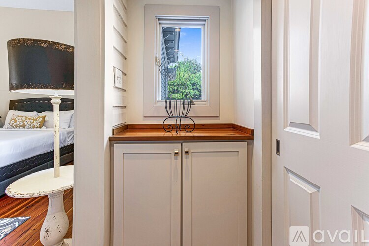A bedroom with a bed, a nightstand, and a window with a view of trees.