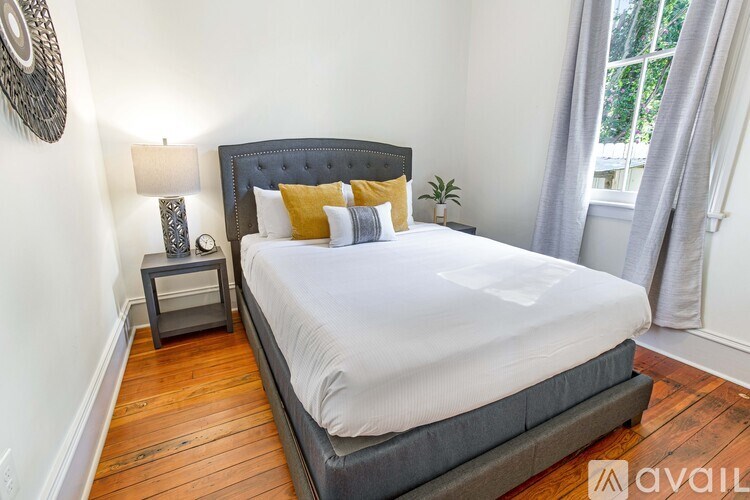 A bedroom with a large bed and a small nightstand with a lamp.