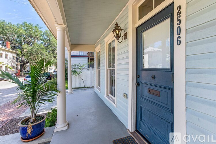 A porch with a blue door and a plant in a blue pot.