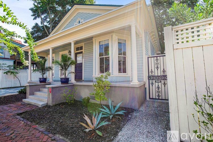 A small house with a white picket fence and a small garden in front.