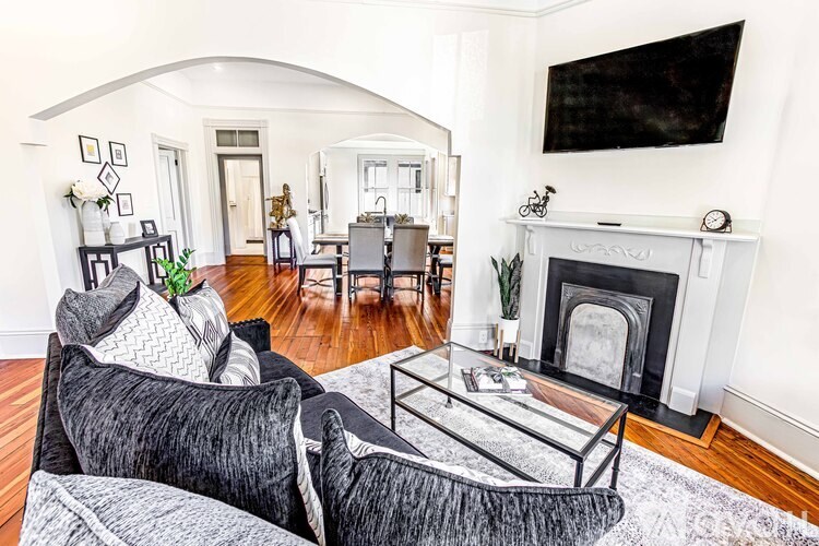 A living room with a fireplace and a grey couch.