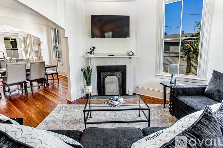 A living room with a fireplace and a television mounted above it.