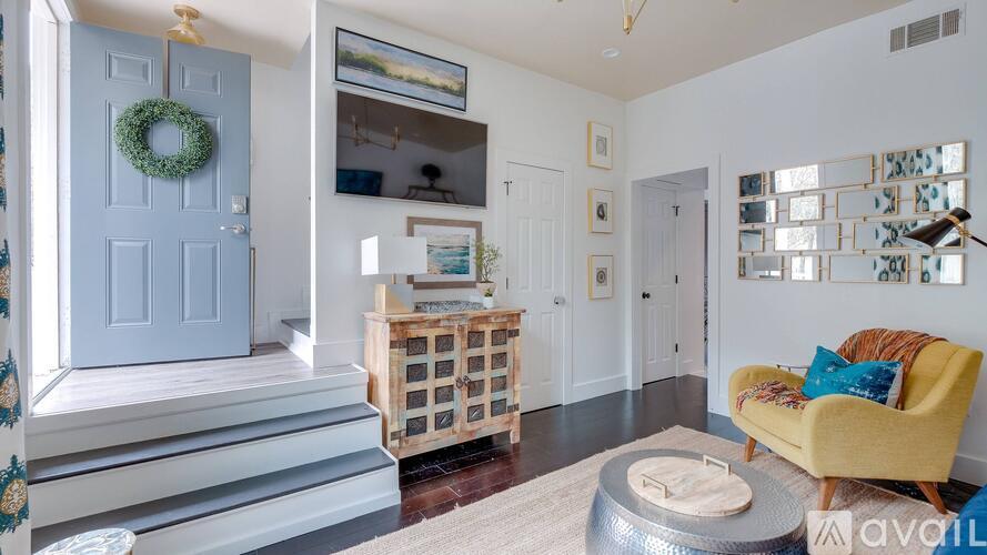 A living room with a yellow chair and a grey ottoman.