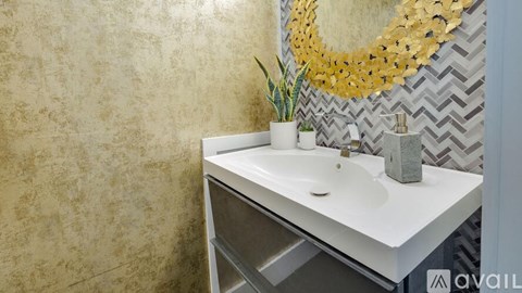 A bathroom sink with a gold mirror above it.