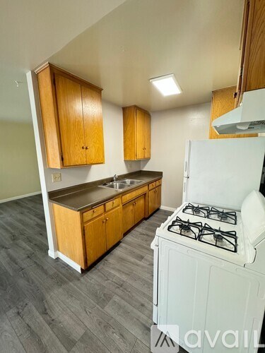 A kitchen with a white gas stove and wooden cabinets.