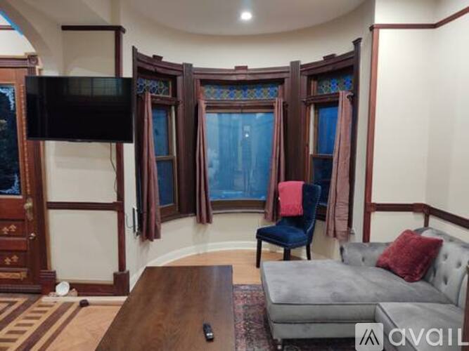 A living room with a grey couch, a wooden coffee table, and a flat screen TV mounted on the wall.