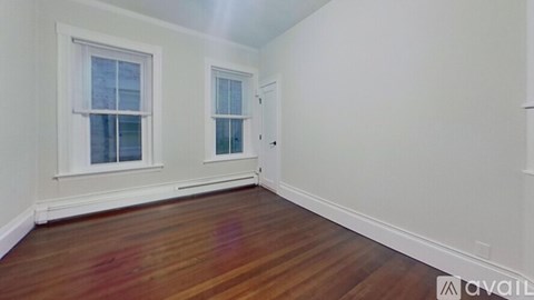 A room with wooden floors and two windows.