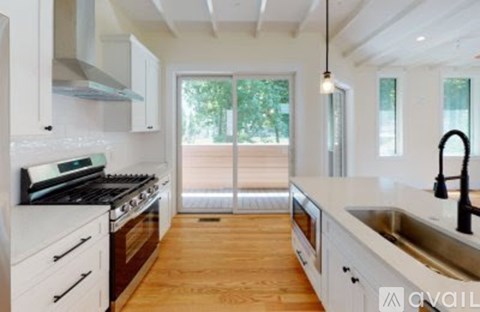A modern kitchen with white cabinets and a black stove top.